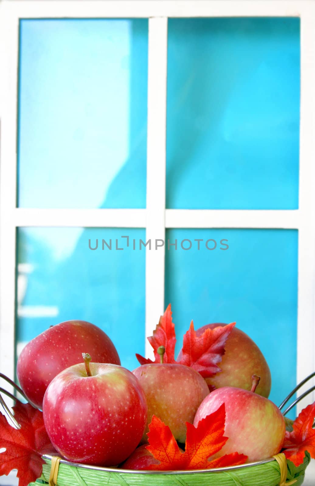 Basket of apples and fall leaves in front of a fake window. Copy space available.