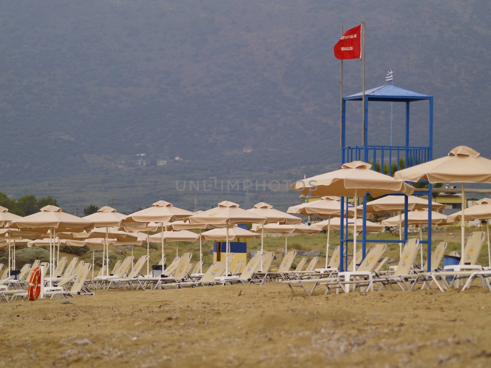 empty beach in greece, red flag on lifeguards tower