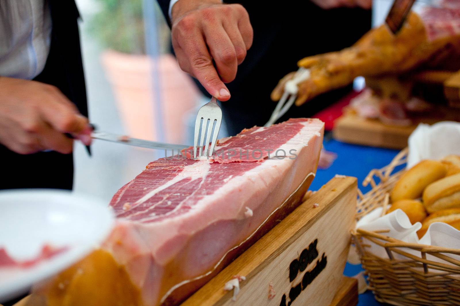 Waiter is slicing Italian raw ham