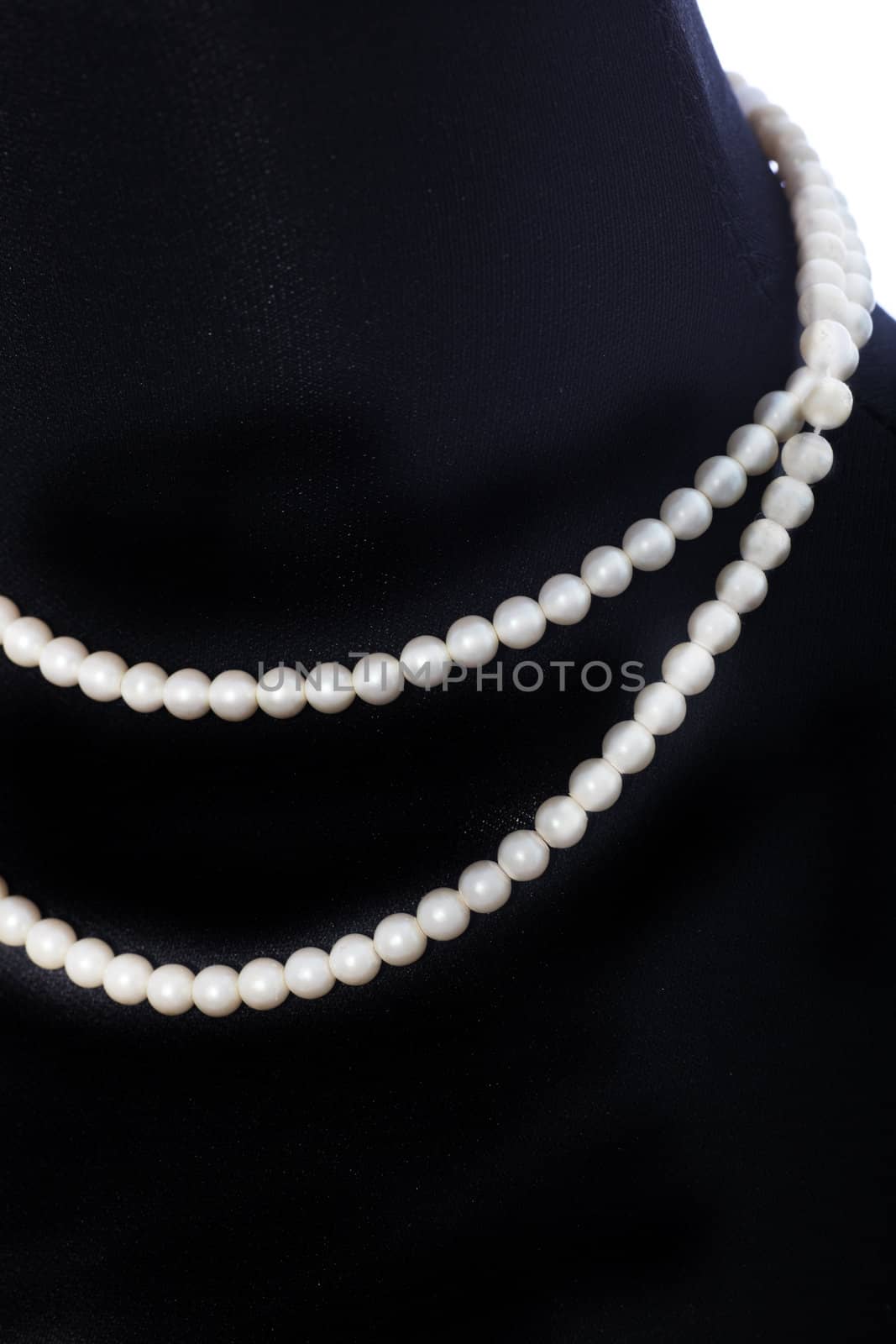 Double string of matched pearls displayed around the neck of a black mannequin