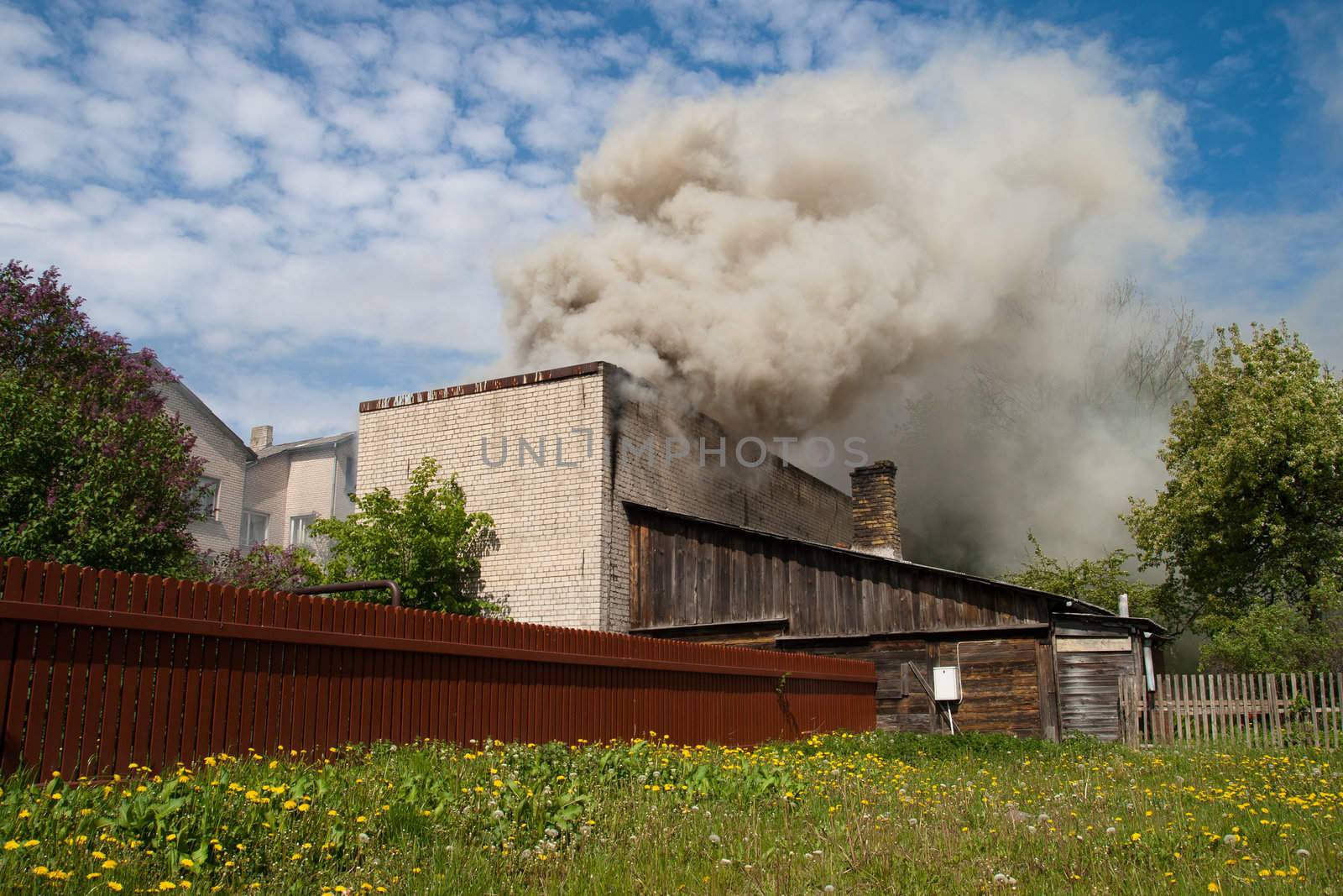 fire in city building, with white smoke to the blue sky