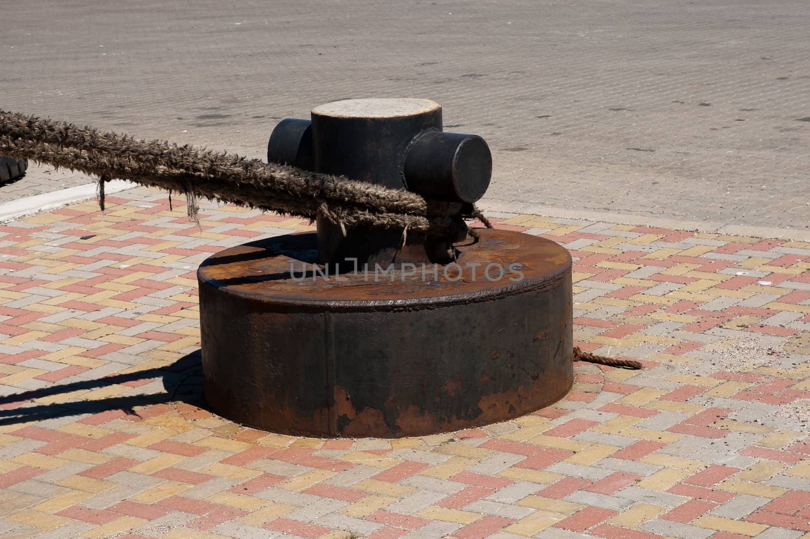 A rusting mooring bollard and mooring ropes