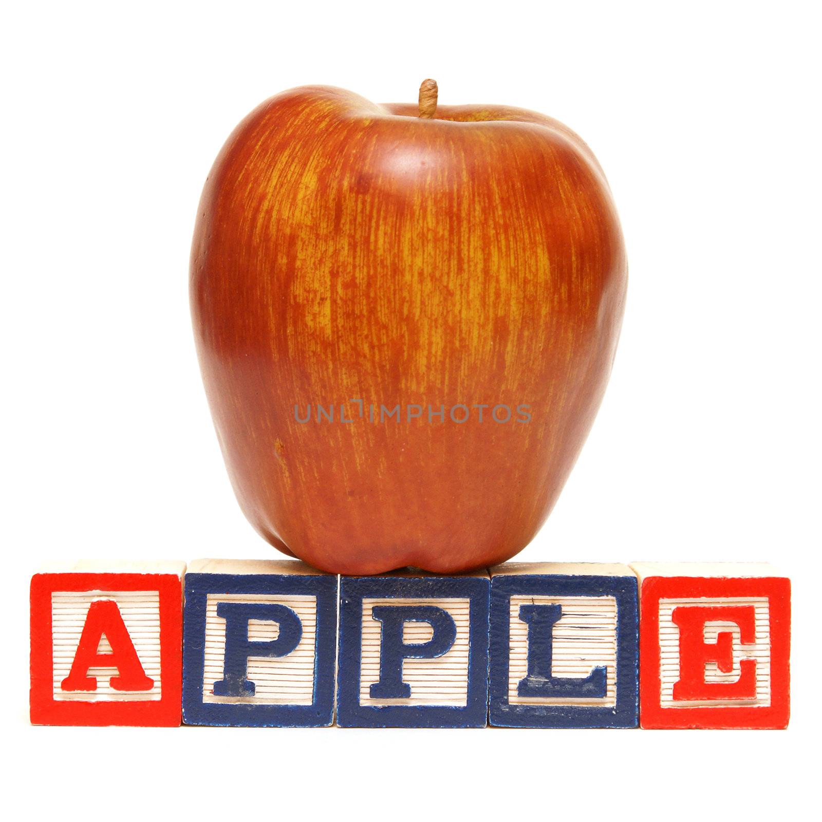 Alphabet blocks spell out the word apple with the healthy fruit being displayed.
