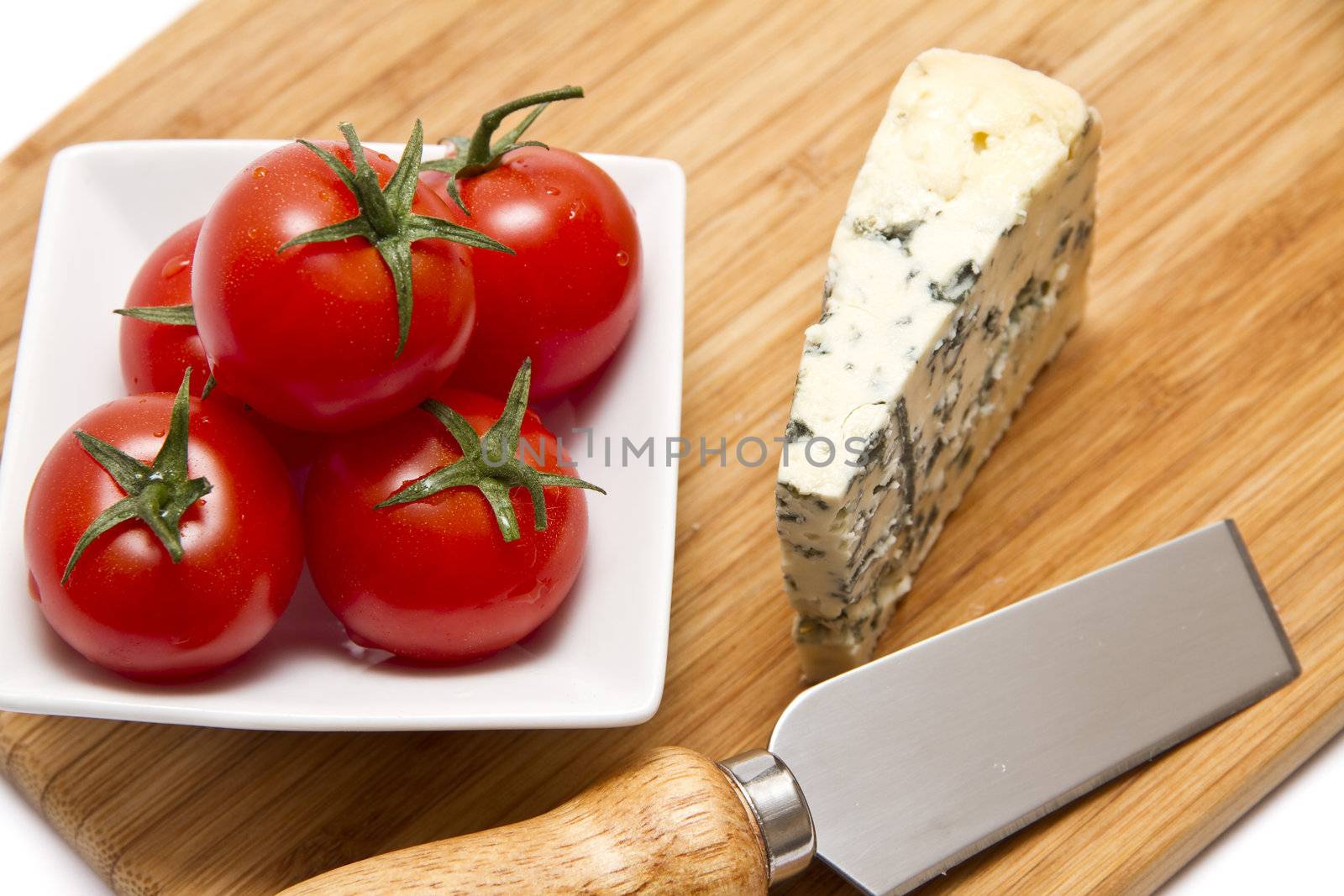 Blue cheese and cherry tomatoes on chopping board by caldix