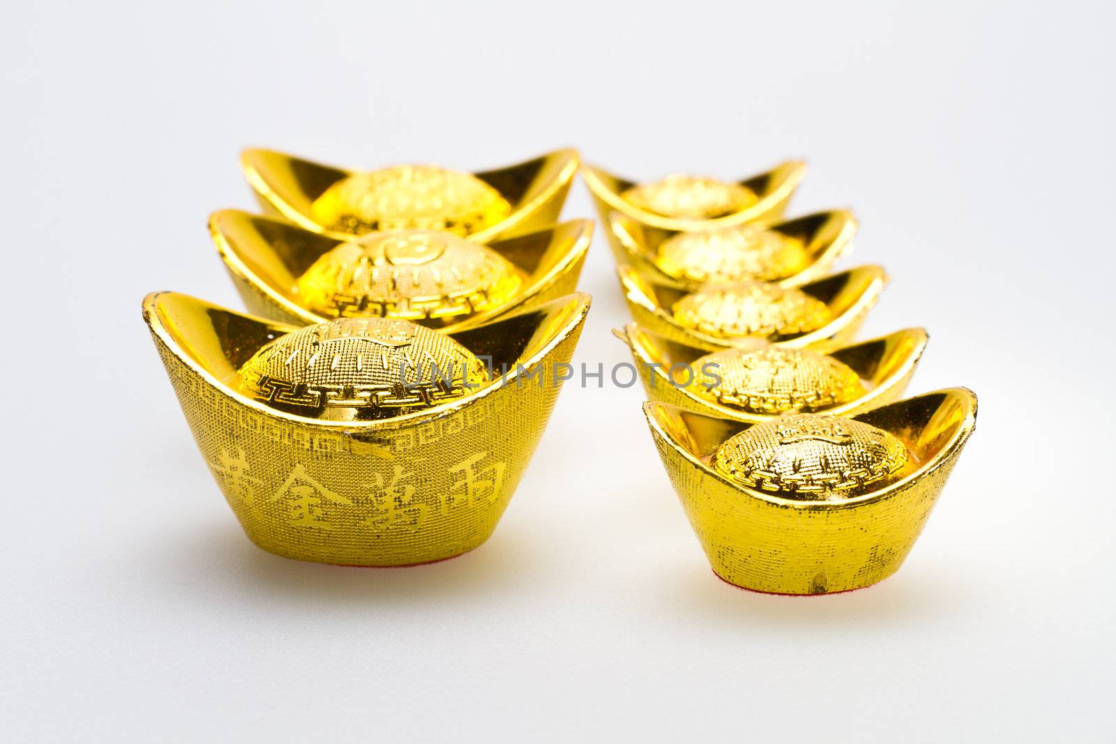 Chinese gold Ingots of various size lie up on white surface