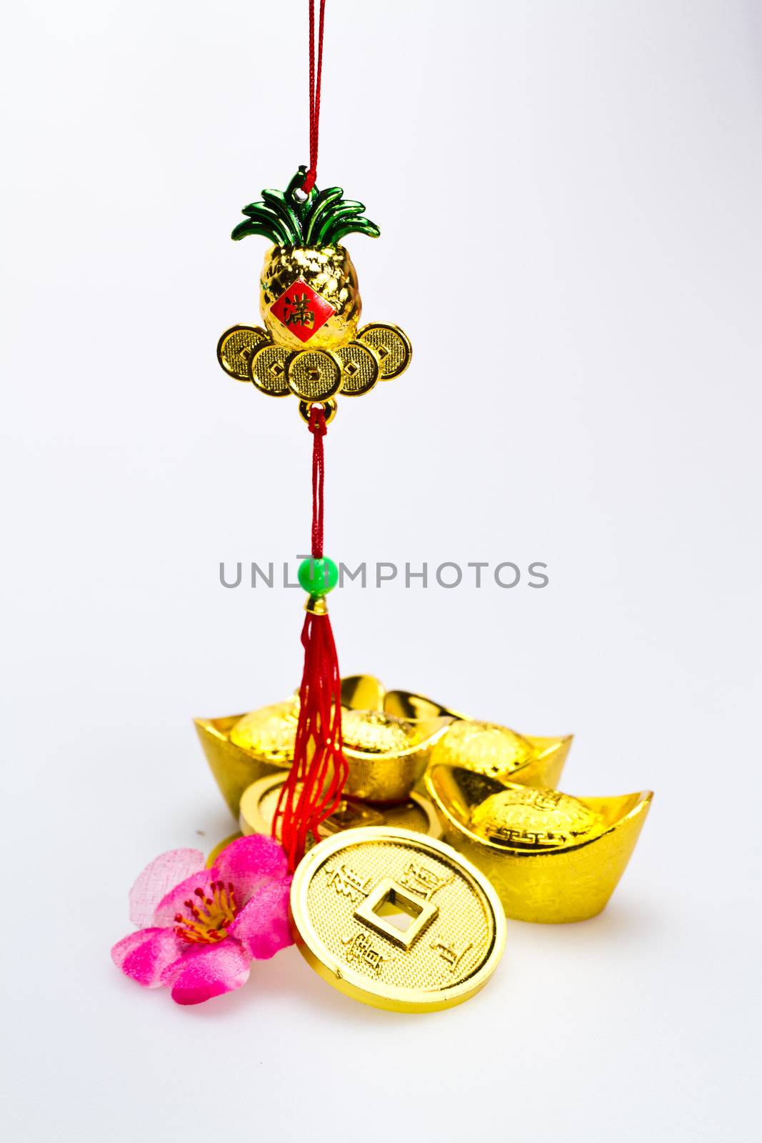 Golden ineapple for chinese new yer celebration with ingots and coins against white surface