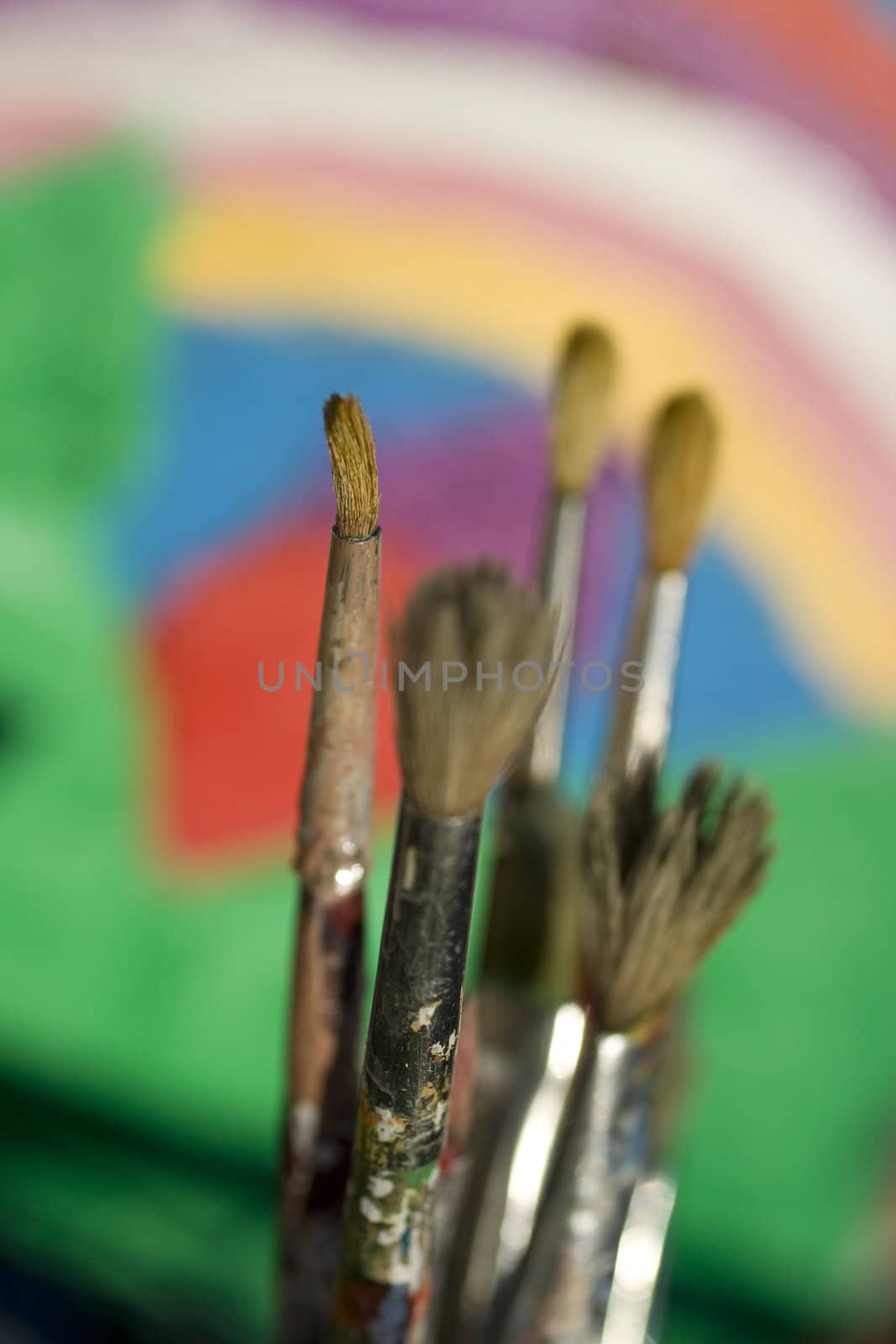 Paintbrushes and painted canvas in the background