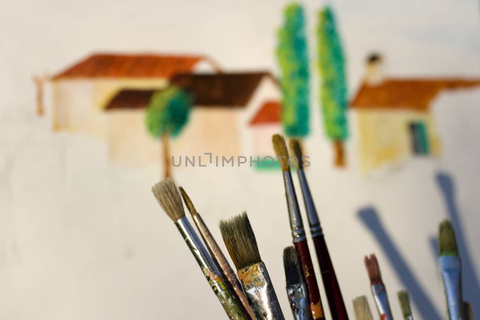 Paintbrushes and painted canvas in the background