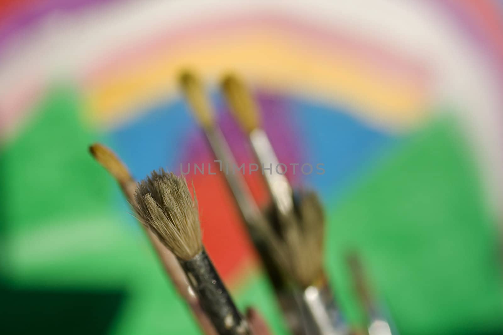 Paintbrushes and painted canvas in the background