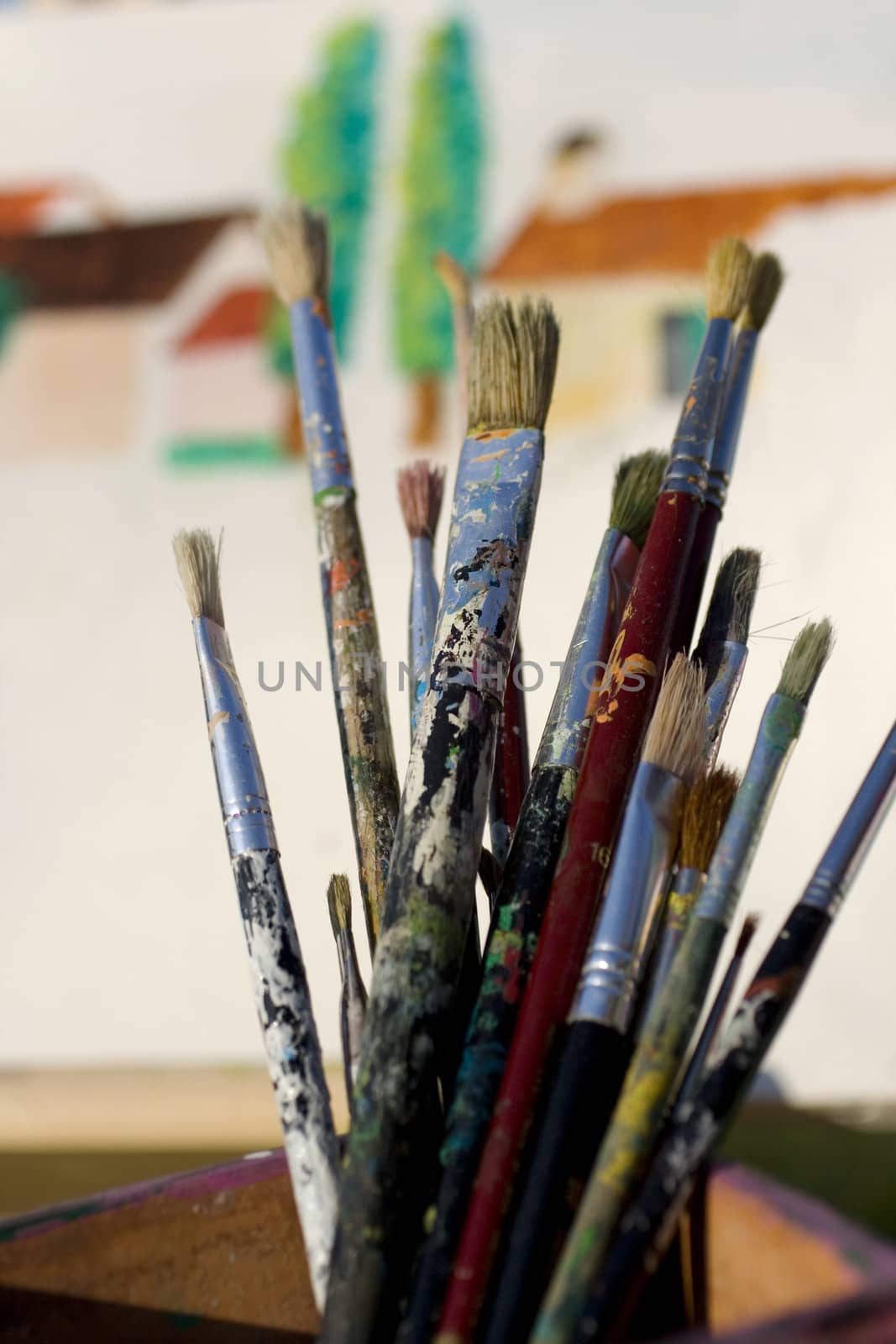 Paintbrushes and painted canvas in the background