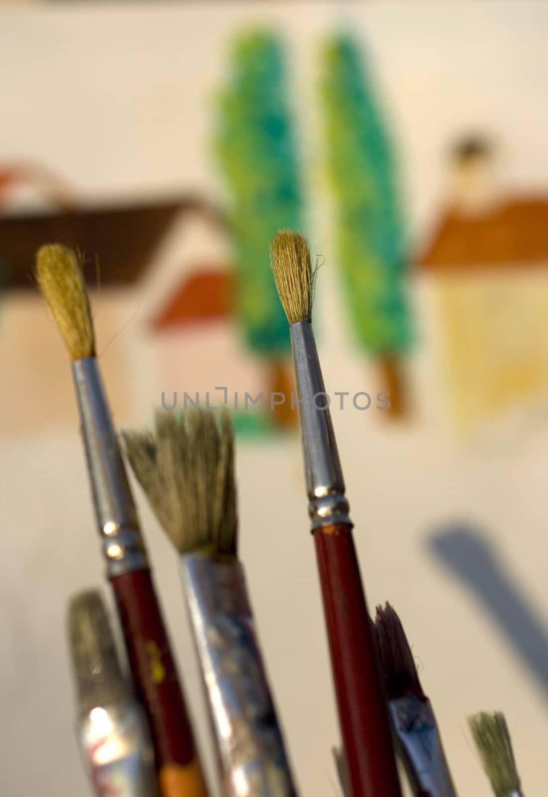 Paintbrushes and painted canvas in the background