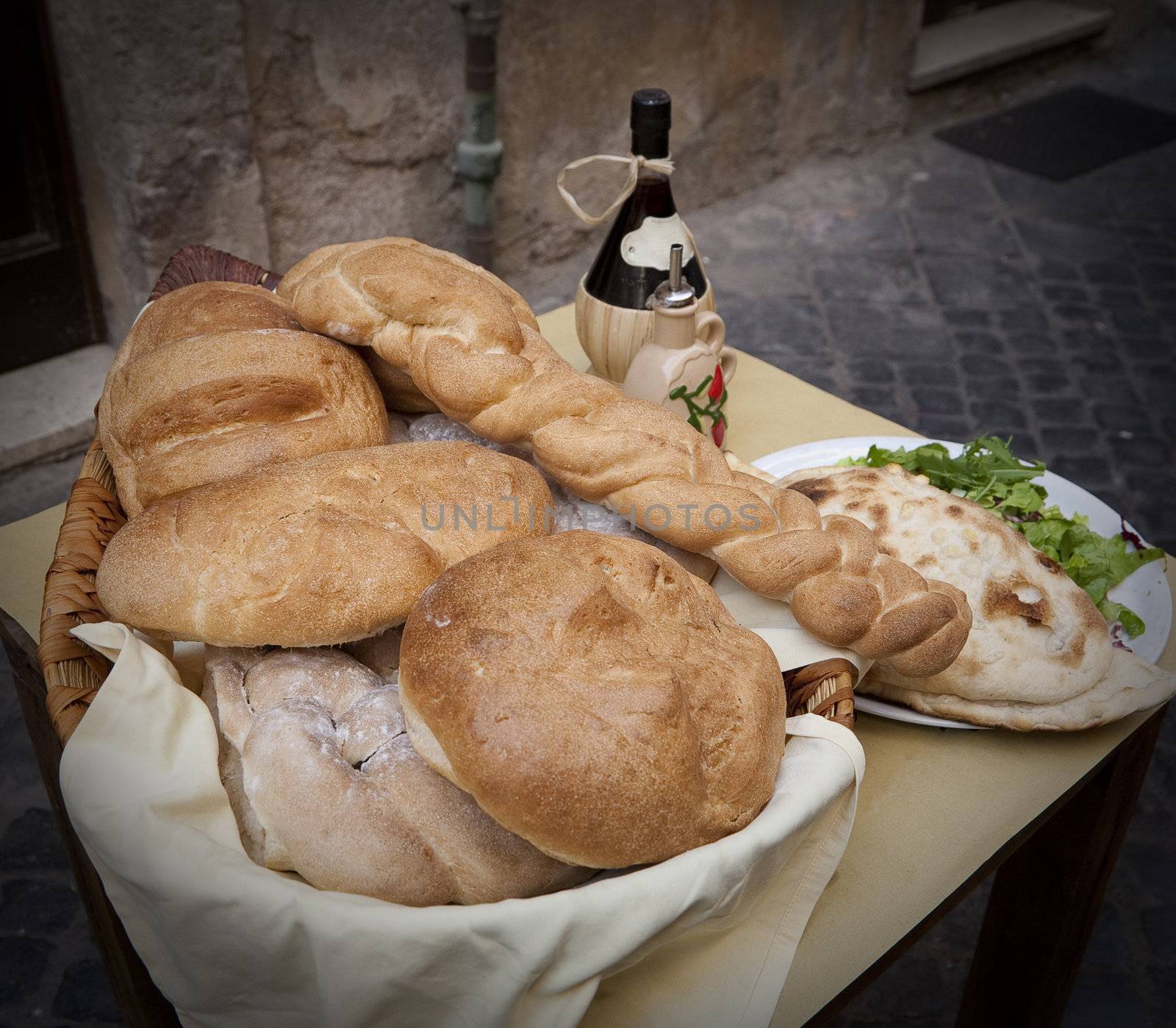 Various loaves in a basket and a bottle of wine seen outside a Roman restaurant.