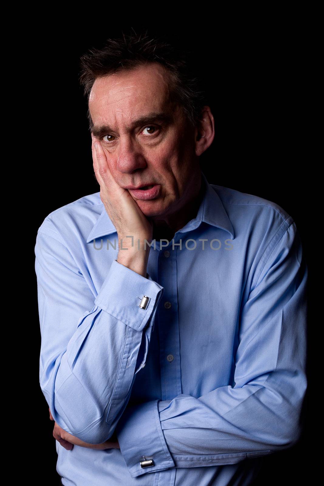 Sad Anxious Depressed Middle Age Business Man with Hand to Chin Black Background