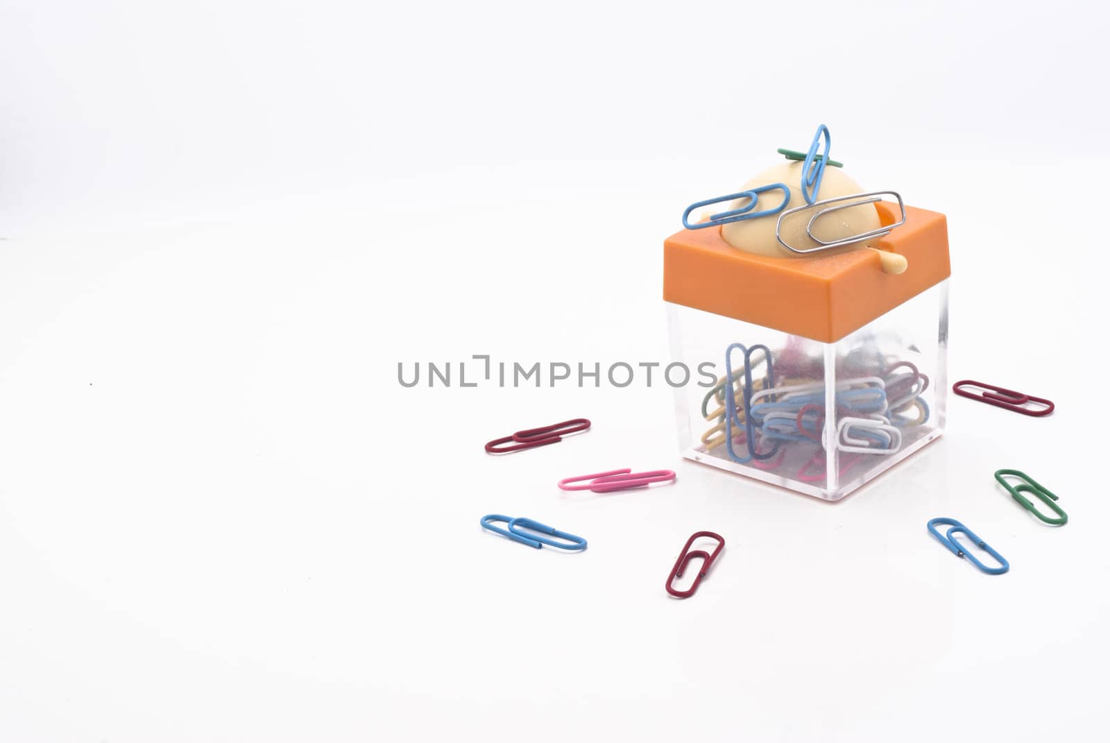 Colorful plastic coated paper clips in clear innovative container with magnet, isolated on white background