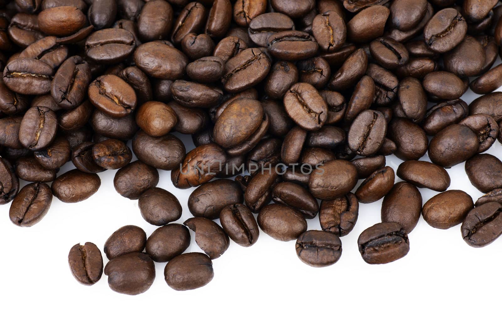 Beautiful macro of dark roast coffee beans over white background with copy space.
