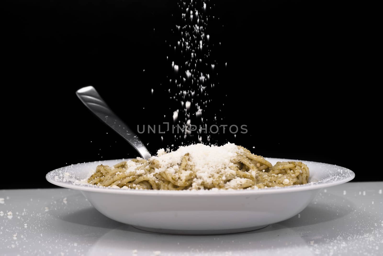 Spaghetti with pesto and cheese isolated on black background