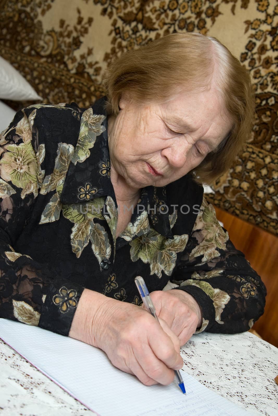 The elderly woman writes the letter