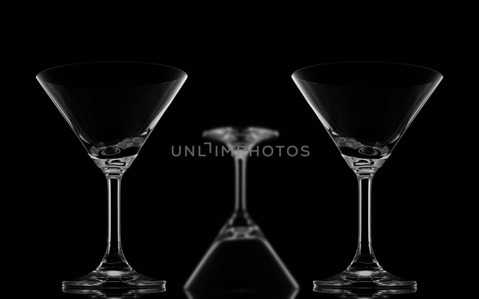 Two Sharp Cocktail glasses and one blur upside down on black background and reflection