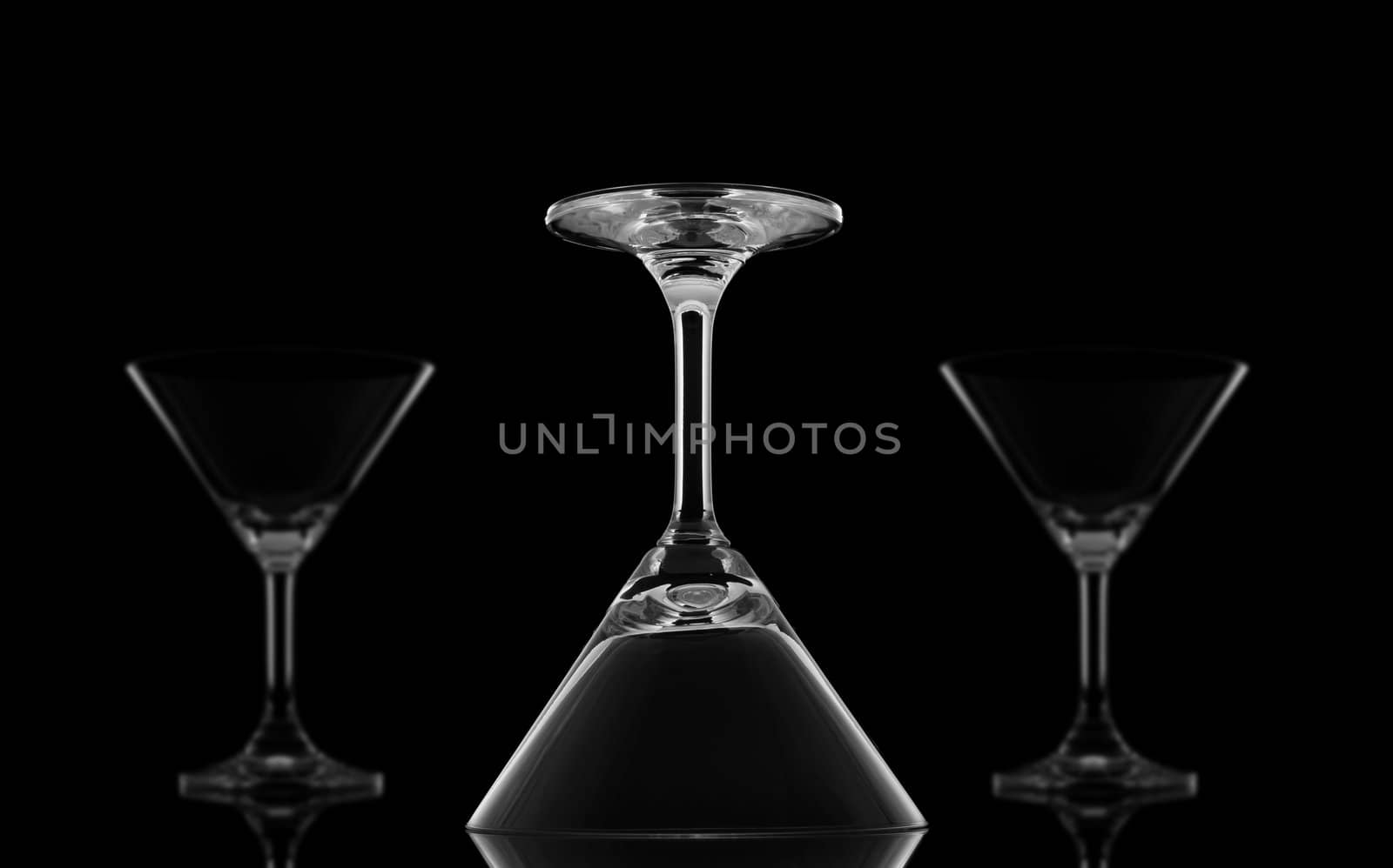 One Sharp upside down Cocktail glasses and Two Blur on black background and reflection