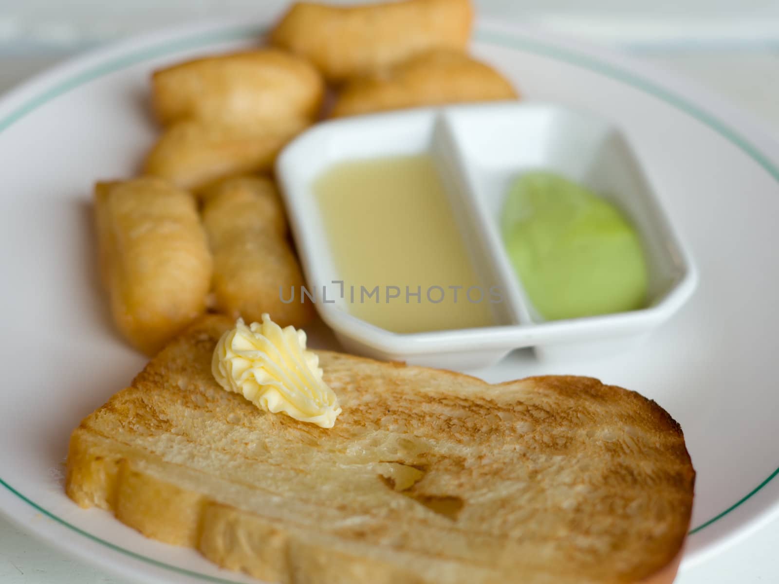 Bread with butter and Deep fried Dough Sticks Custard condensed milk on white table