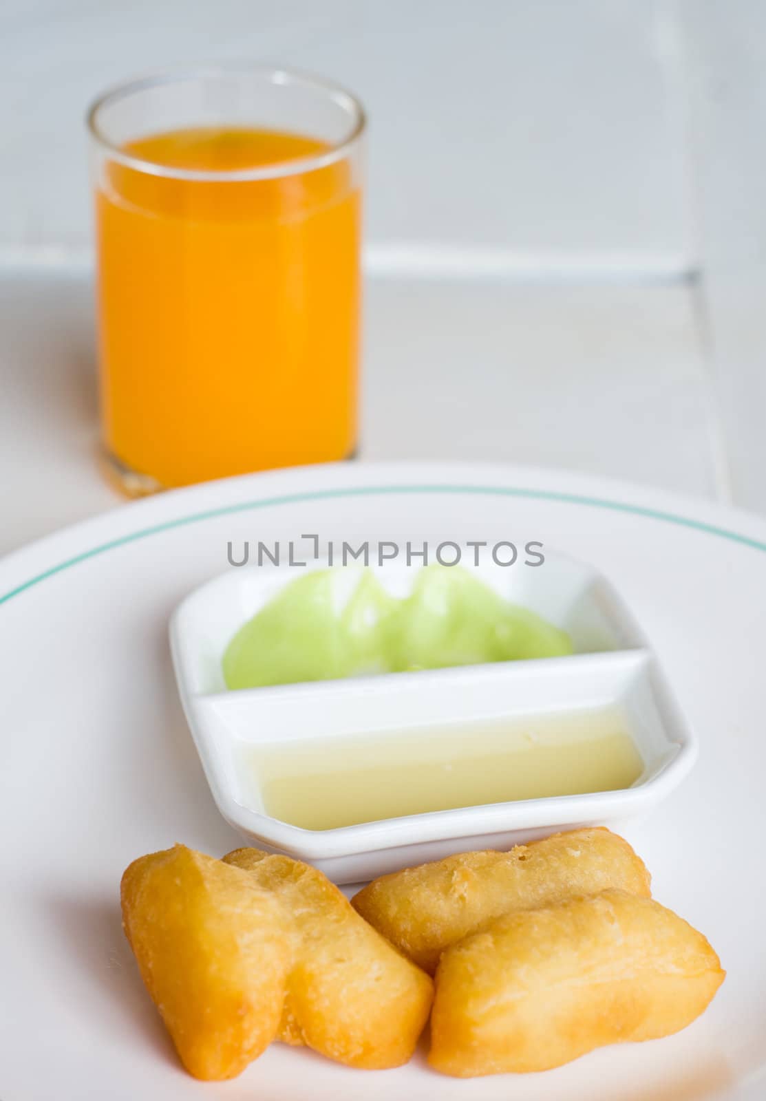 Deep fried Dough Sticks Custard condensed milk and orange juice on white table