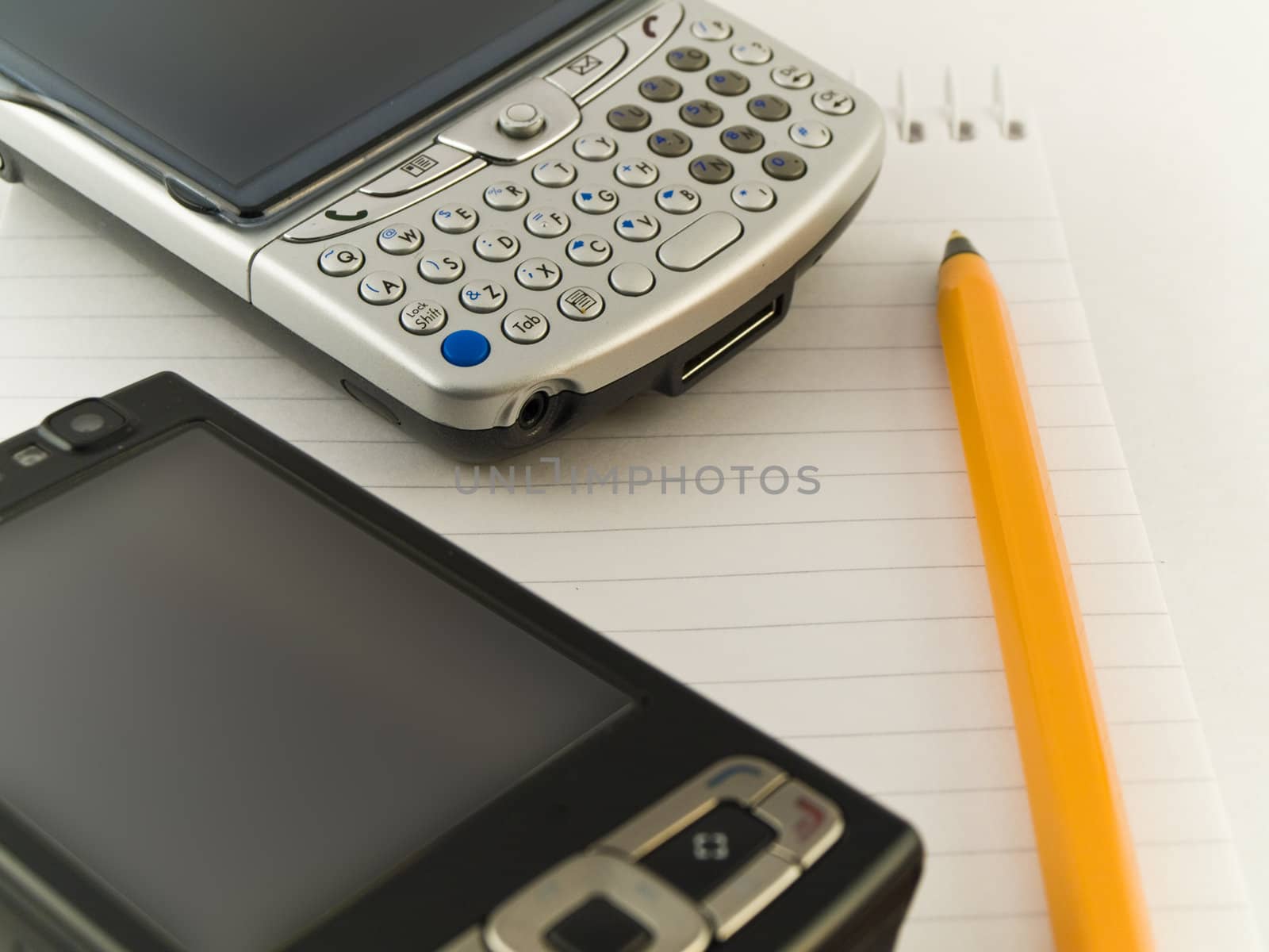 Mobile Phones and Pen on Notepad White Background by bobbigmac