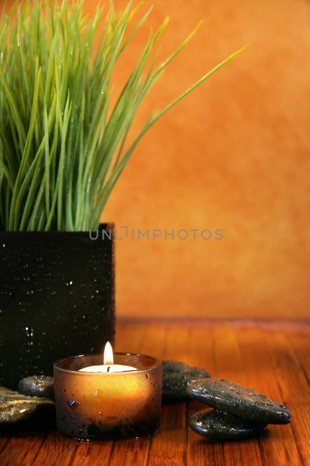 Spa setting with candle, stones and herb grass