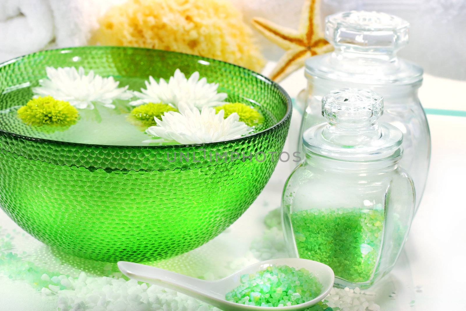 Green bowl with water and flowers ready for spa session