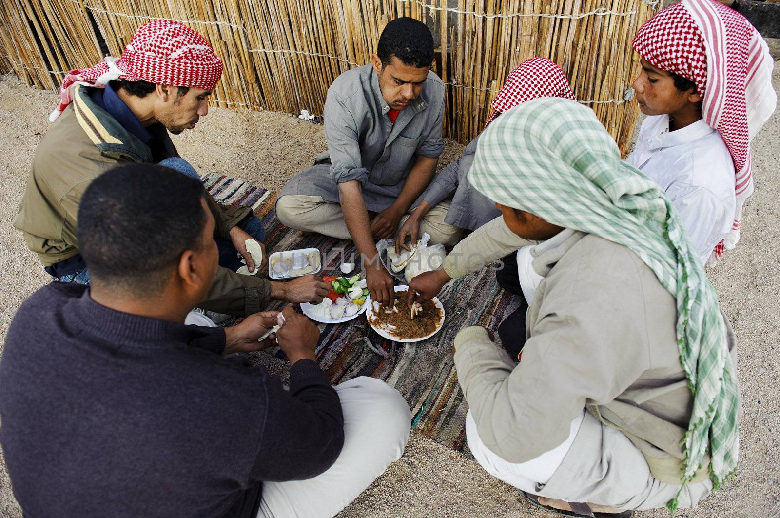 HURGHADA - JAN 30: Bedouin men enjoying traditional arabic breakfast beside a thatch house.Jan 30,2013 in Hurghada,Egypt.