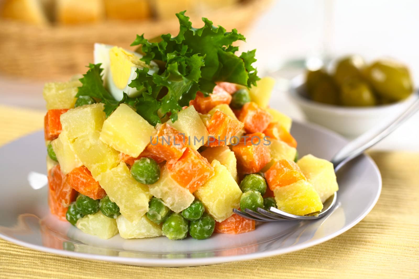 Vegetarian Russian Salad, also called Salad Olivier, made of potato, carrot and peas mixed with mayonnaise (Selective Focus, Focus on the vegetables on the fork and the food in the same plane) 