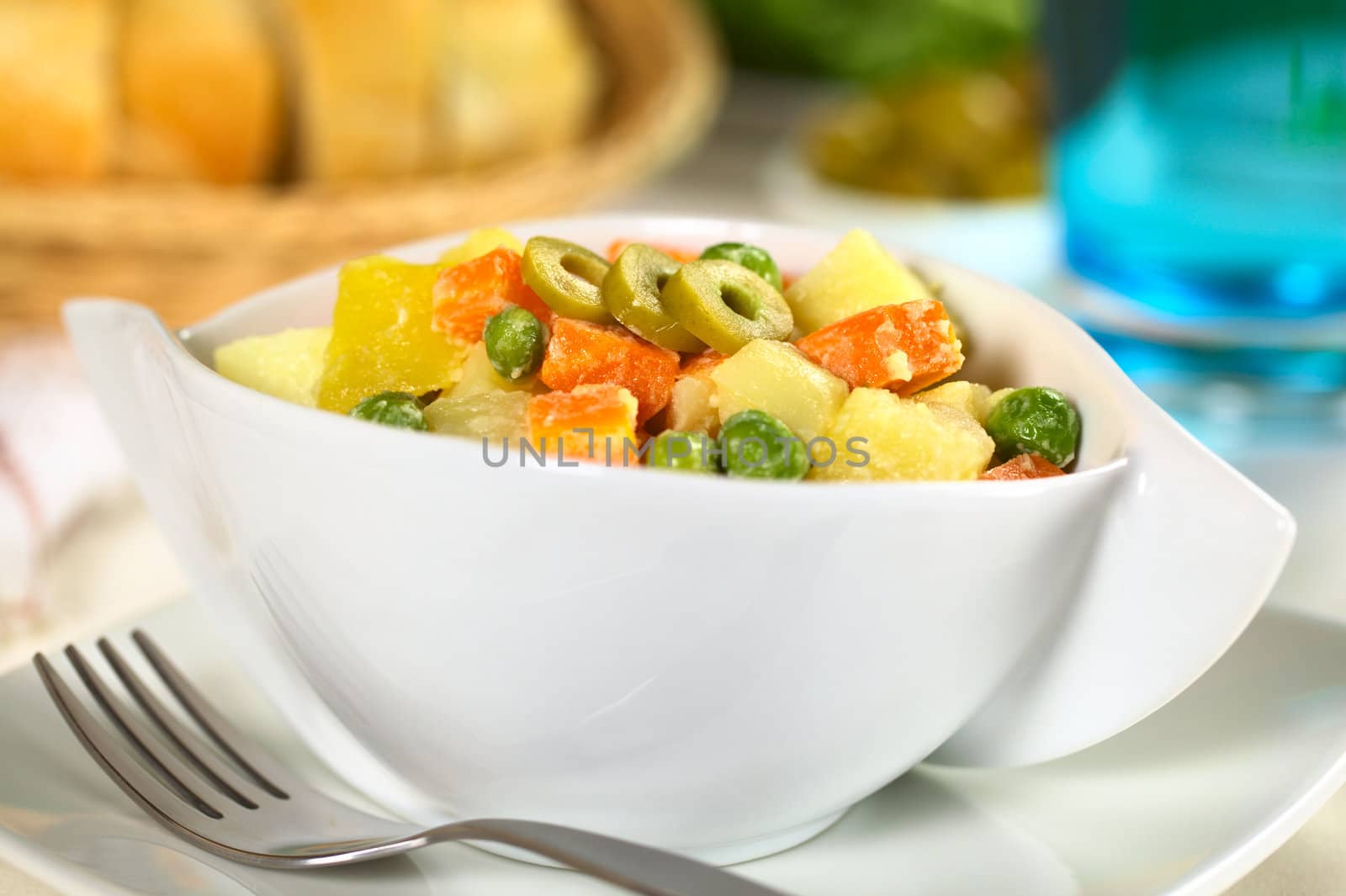 Vegetarian Russian Salad, also called Salad Olivier, made of potato, carrot and peas mixed with mayonnaise garnished with green olive slices (Selective Focus, Focus on the frot of the green olive slices) 