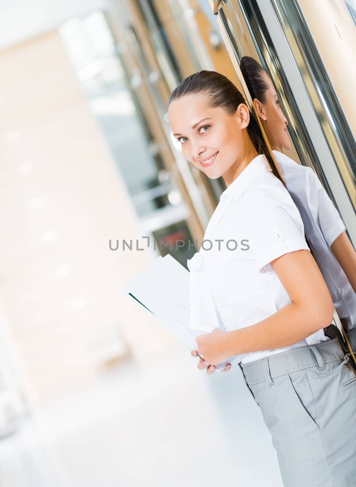 Portrait of a successful business woman in the office, holding papers and smile