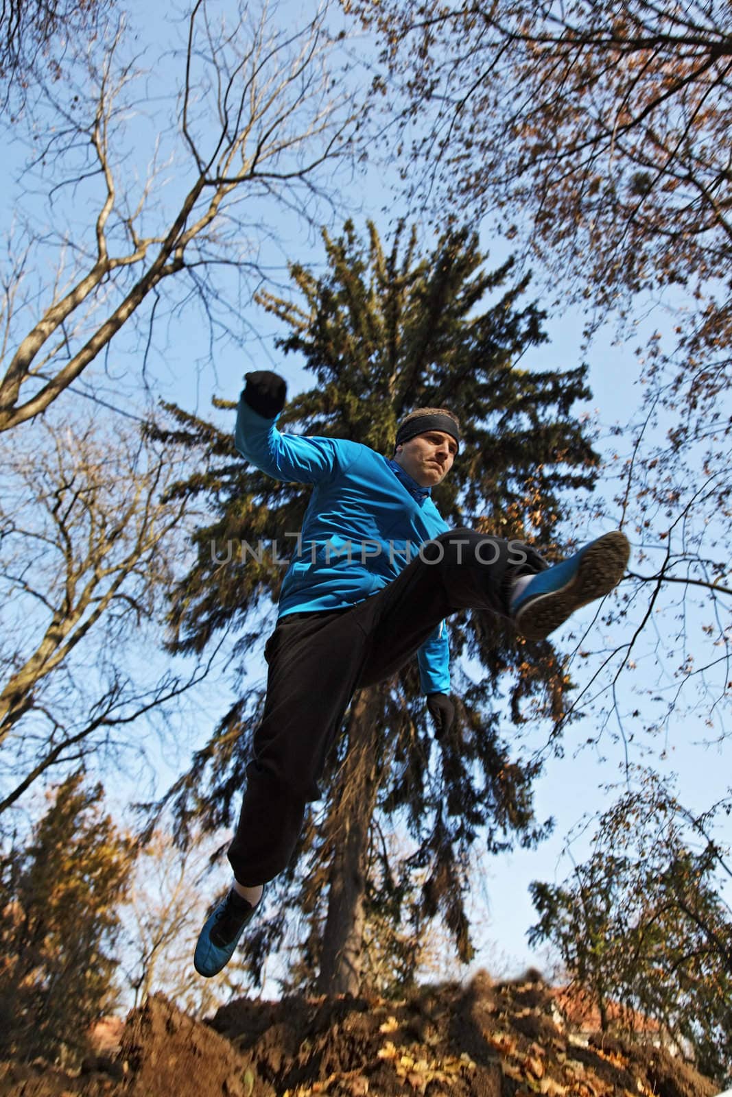 Young man jumping over a hole in a forest.