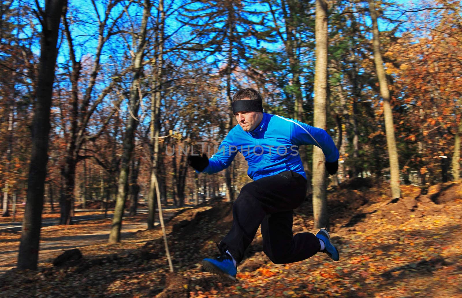 Man jumping over a hole in a beautiful forest in autumn.