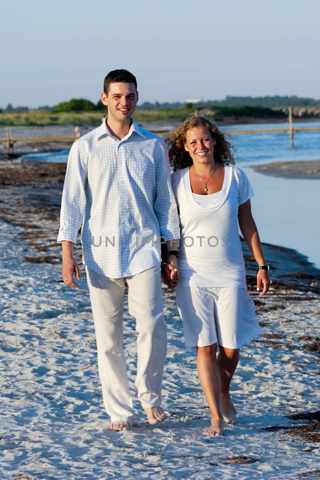 A young happy couple is walking on a beach.