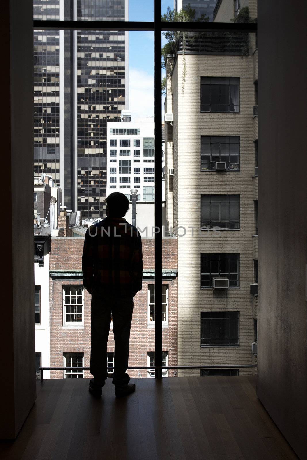 silhouette of a man looking out the window that overlooks a large city