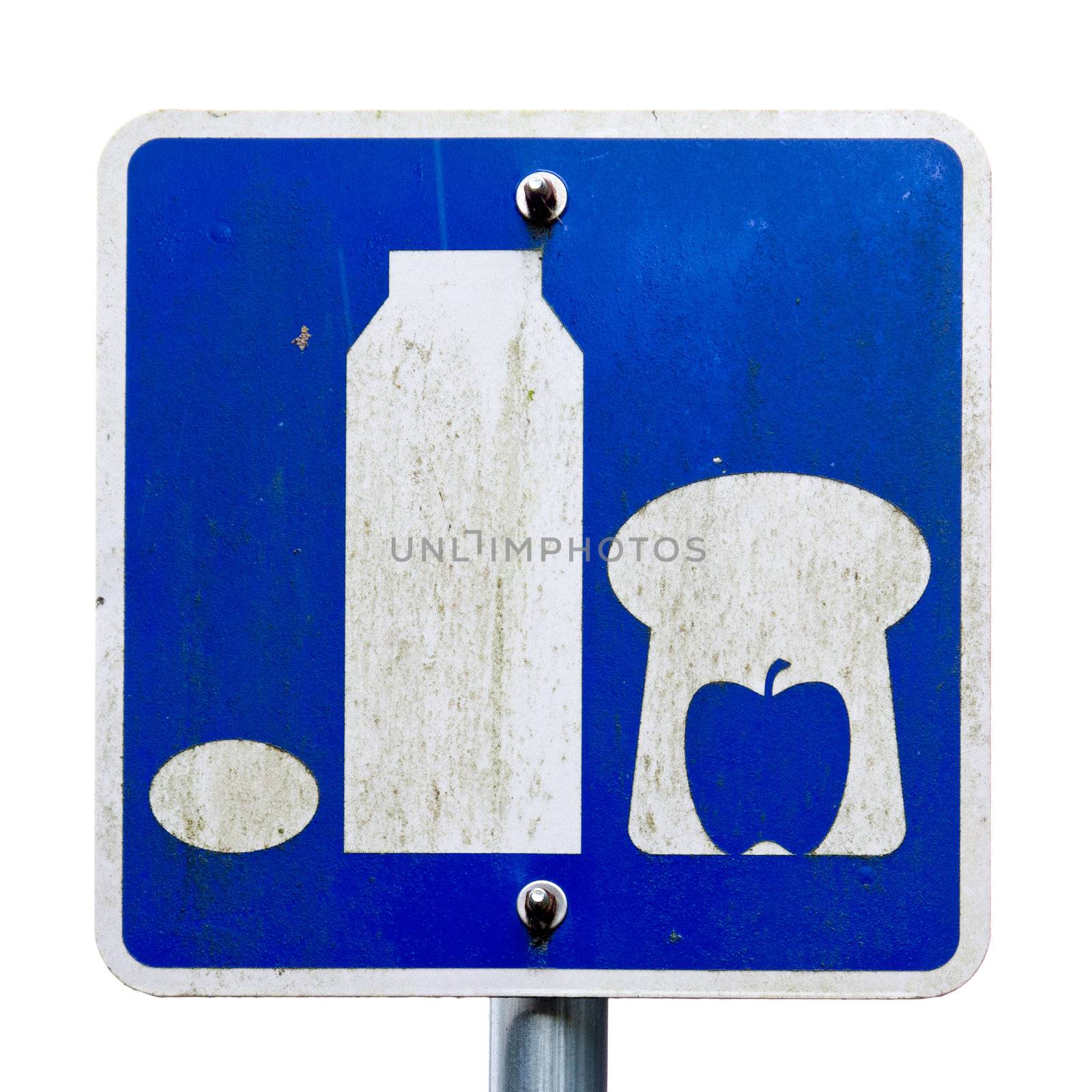 Weathered road sign picturing basic food staple such as milk bread apple and egg