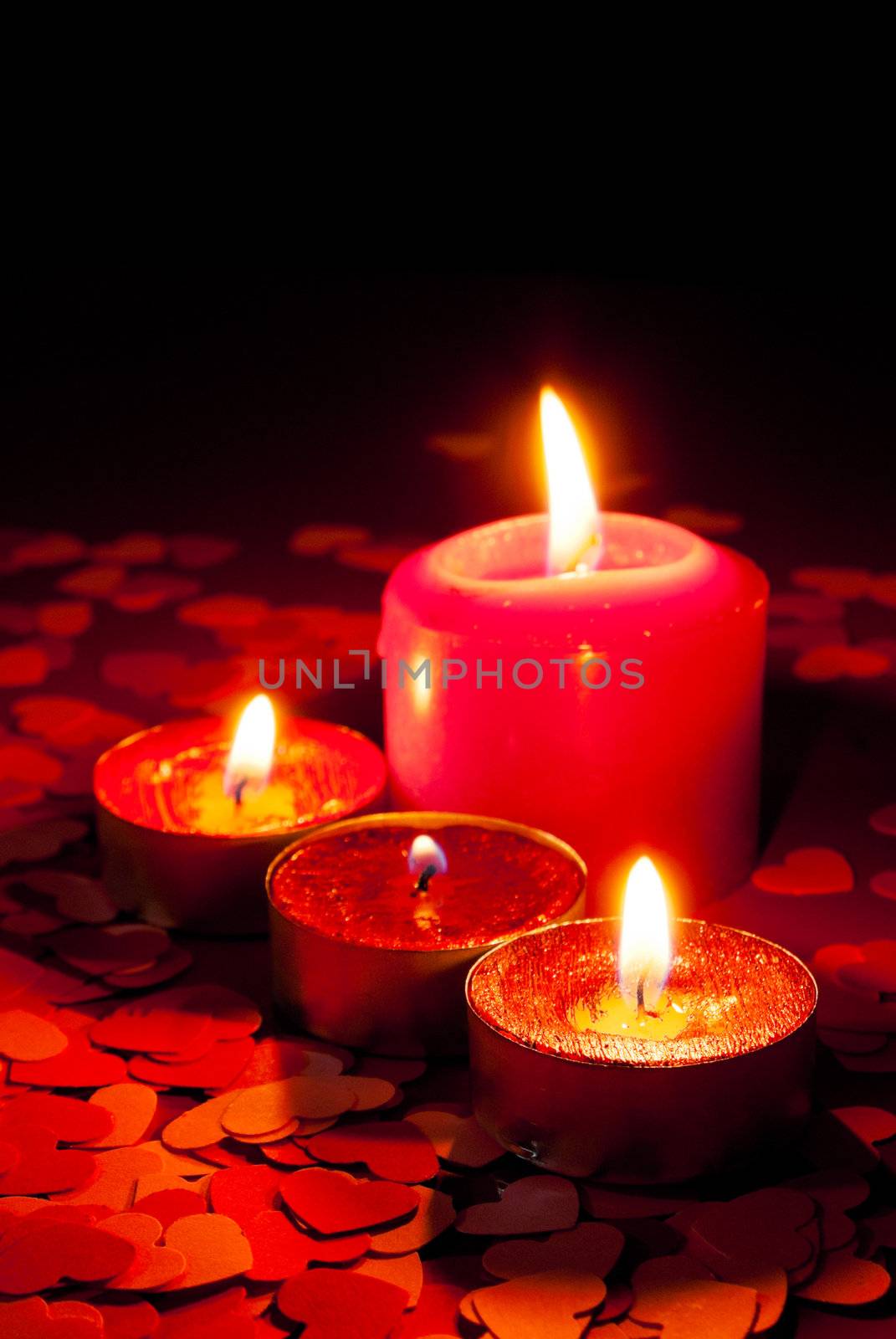 Four burning candles over red background with heart shapes