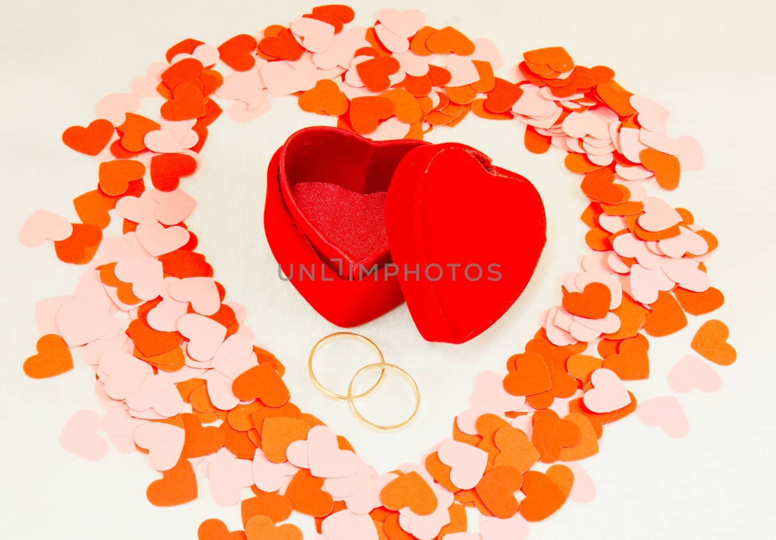 Two rings in front of a red heart shaped box