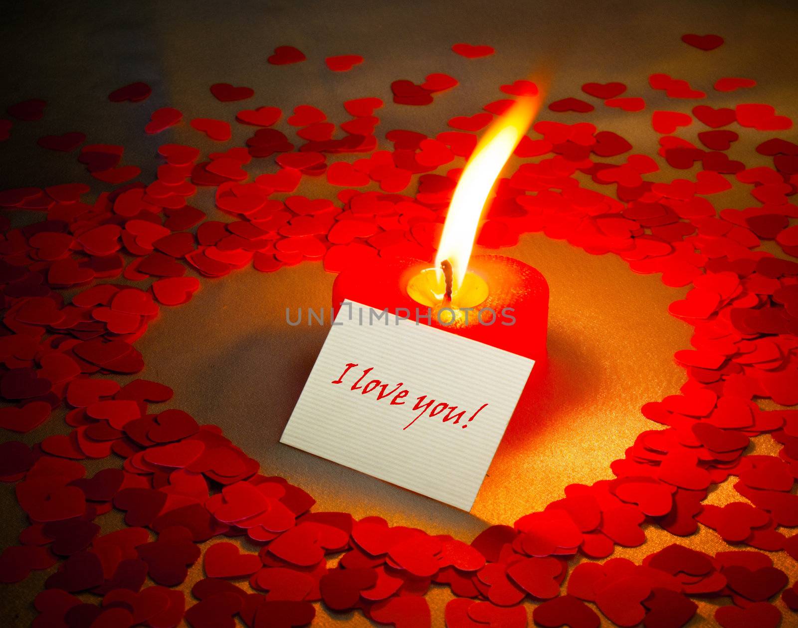 Burning heart shaped candle and a card with 'I love you' writing