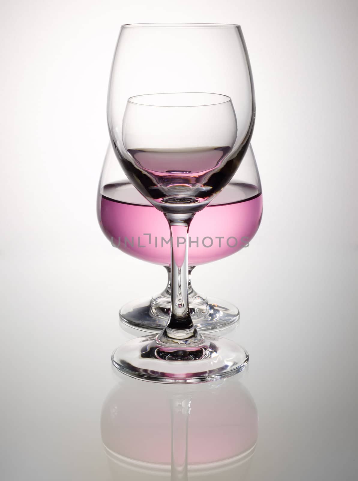 Pink wine in brandy glass overlap and reflection on white table