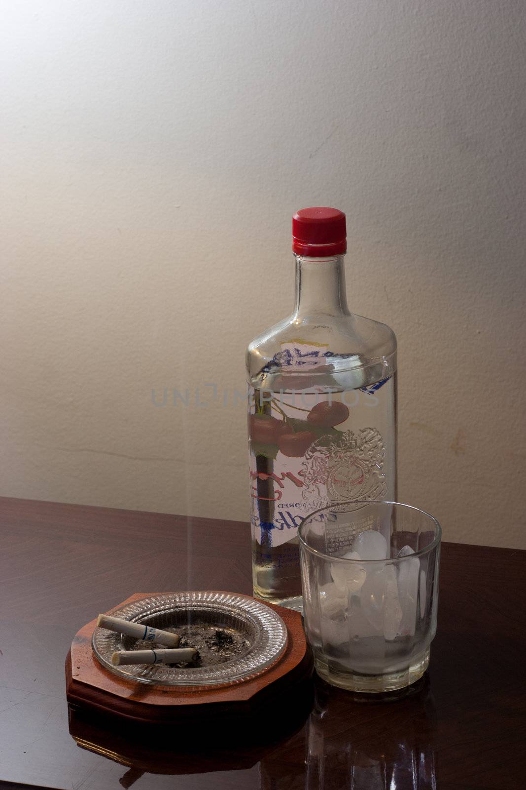 Glass with ice and a liquor bottle ready to be poured.