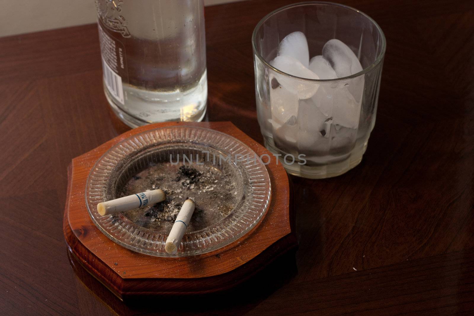 Glass with ice and a liquor bottle ready to be poured.