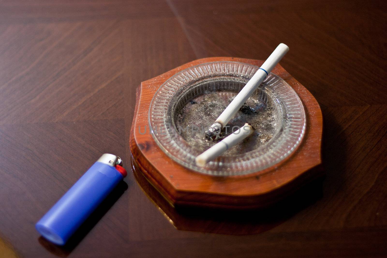 Cigarettes in ash tray with lighter on coffee table