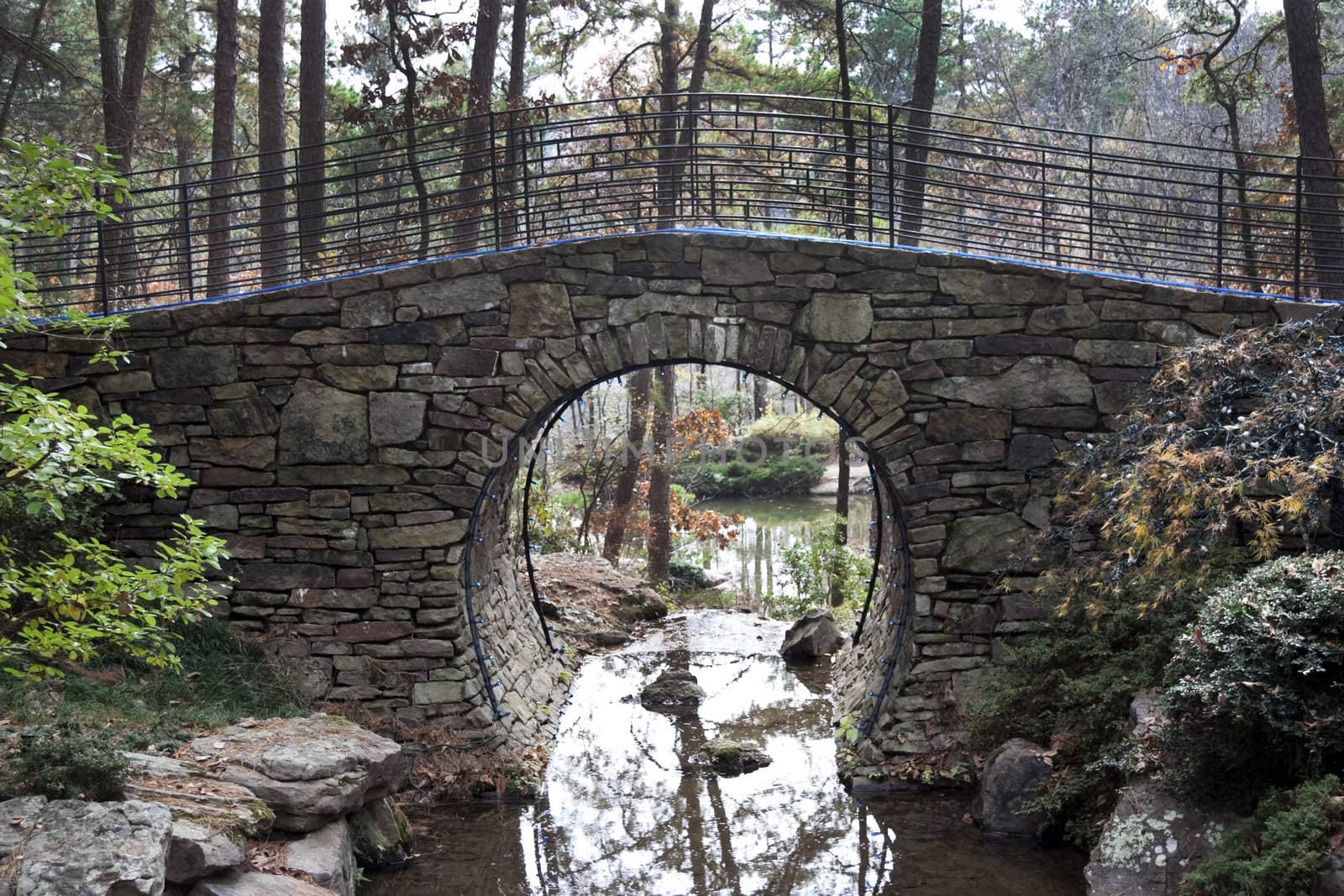 A bridge spanning over a small pond made of stone