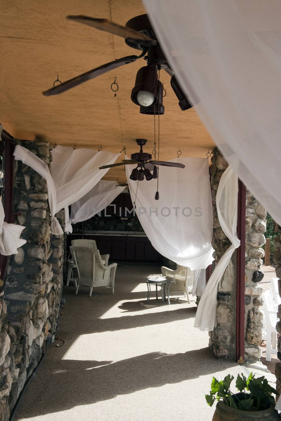 An outdoor seating patio with white sheets blowing in the wind