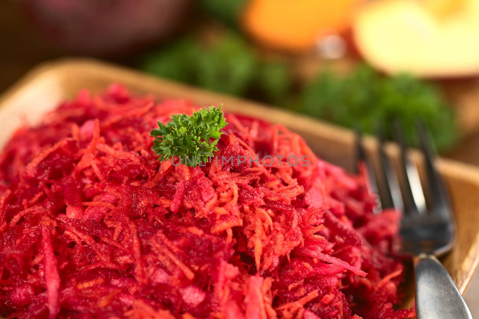 Fresh grated beetroot, carrot and apple salad garnished with a parsley leaf (Selective Focus, Focus on the front of the parsley leaf)