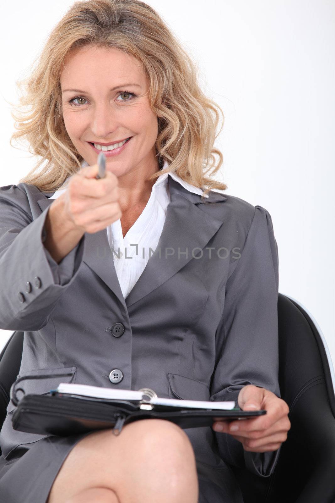 Smiling businesswoman pointing her pen at the camera by phovoir