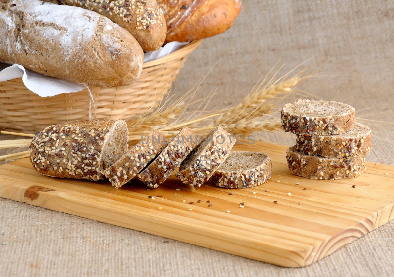 Diverse bread with slices of bread with grains on a wooden board with ears of wheat