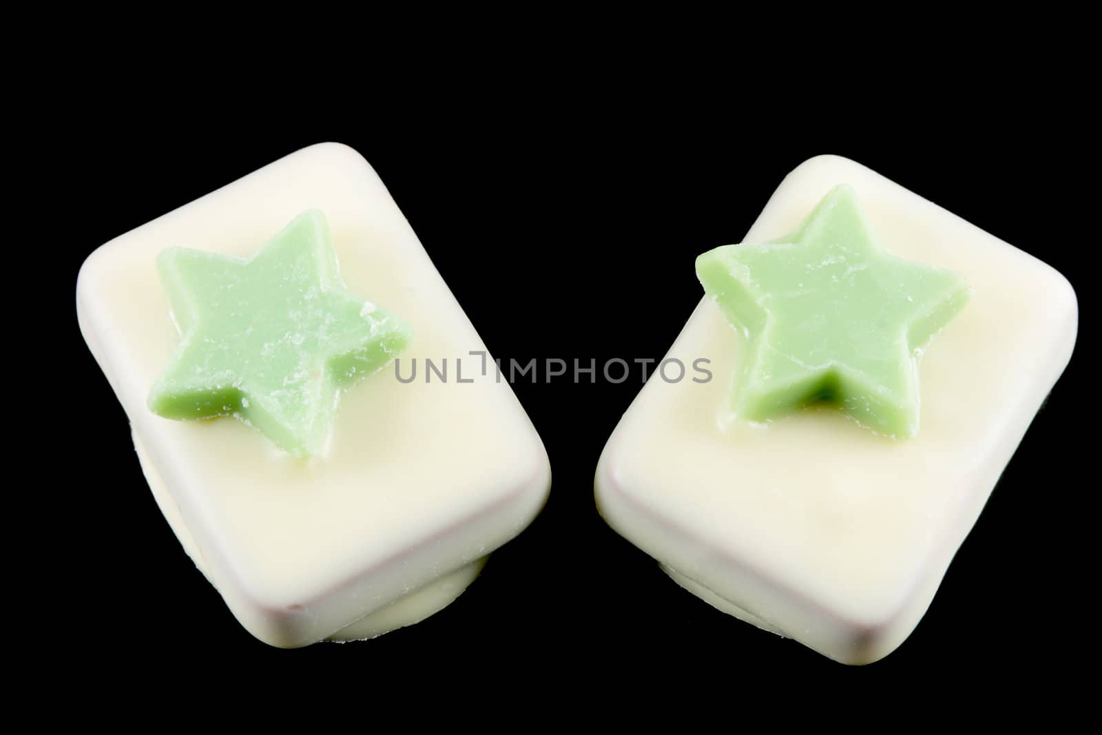 Two pastries of white chocolate with stars green isolated on a black background